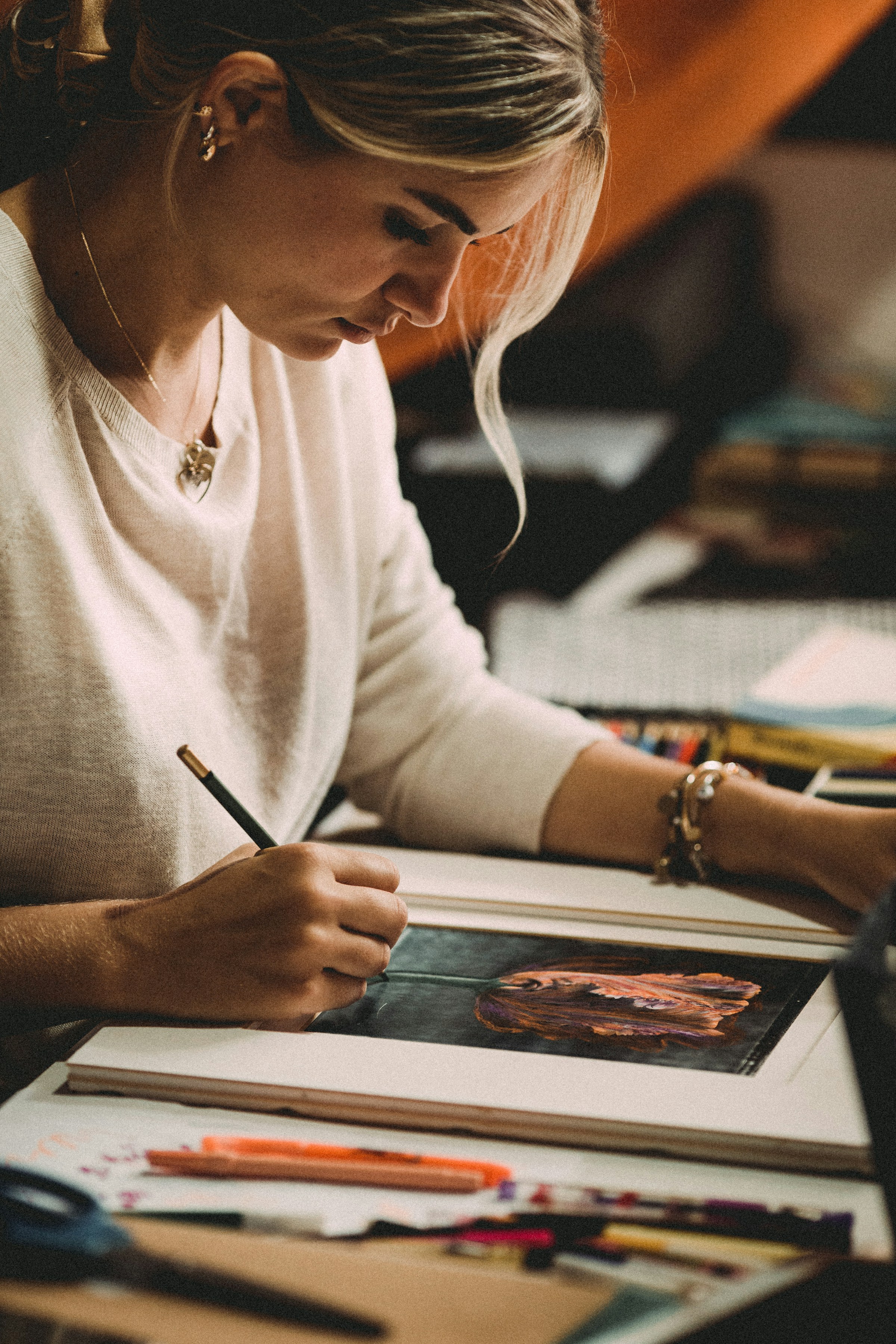 A woman sitting at a table painting after reviewing her ADHD treatment options and tapping into her creativity.