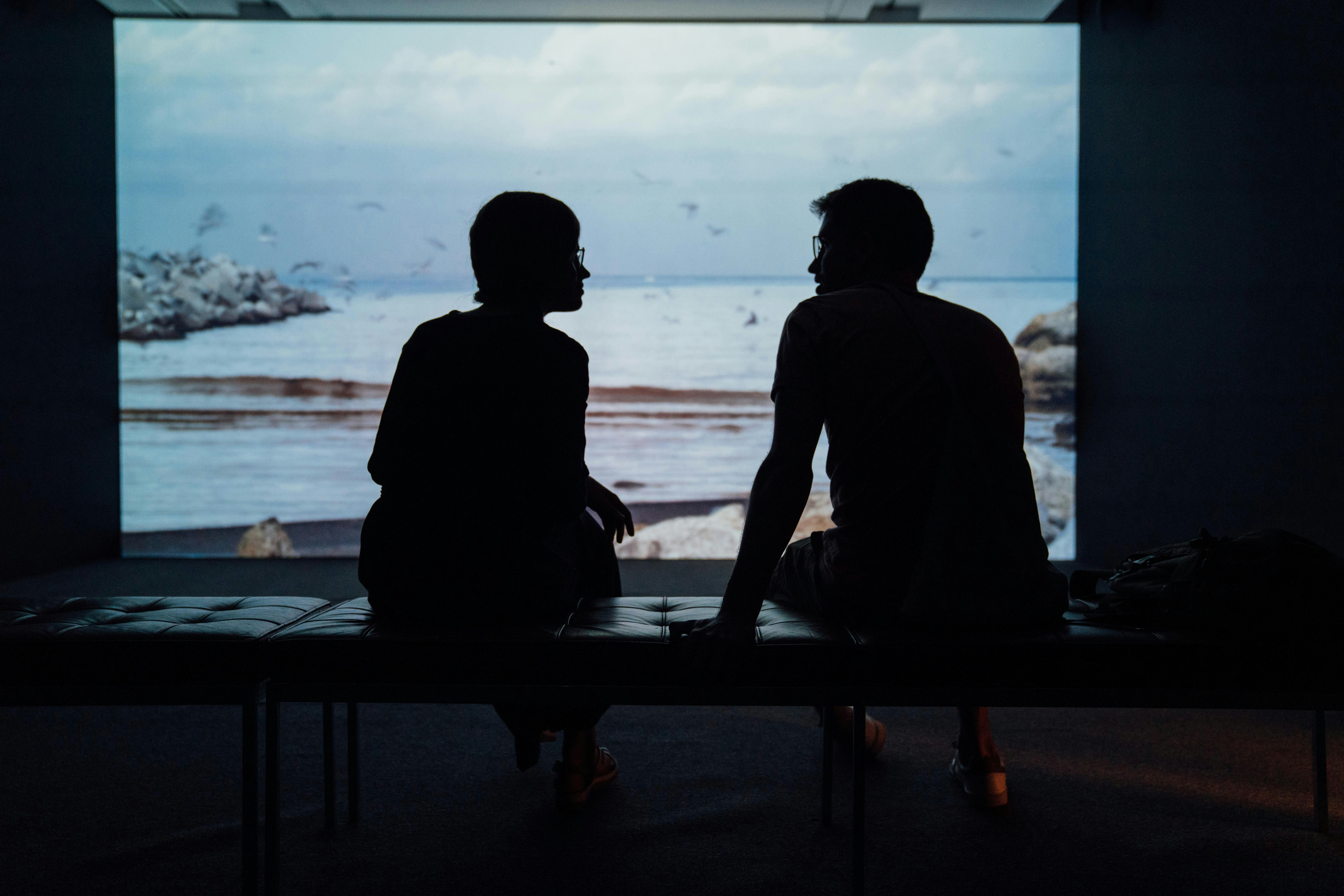 Silhouette of a couple sitting in an aquarium discussing one of them having an anxious attachment style.