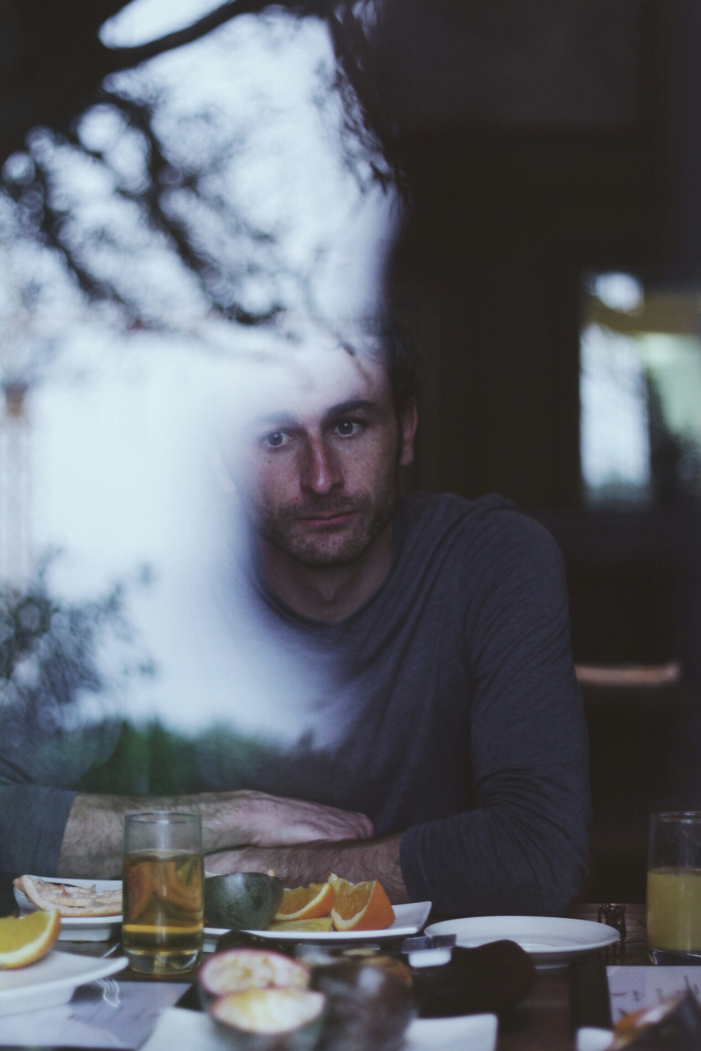 A man sitting at a kitchen table, staring off into the distance and thinking about going to therapy for his burnout symptoms.