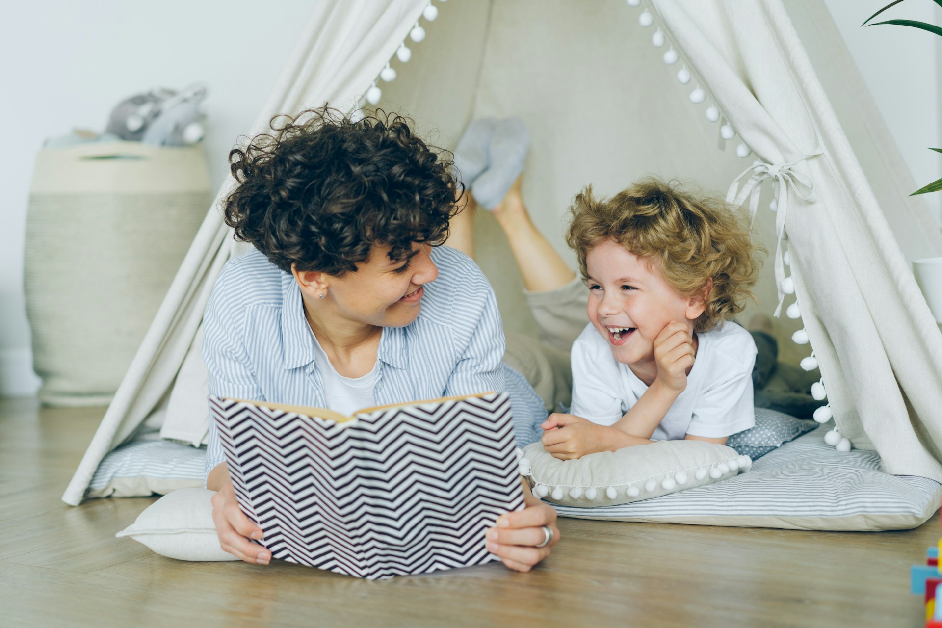 A parent reading to their child in a tent after attending a class on co-parenting after divorce.