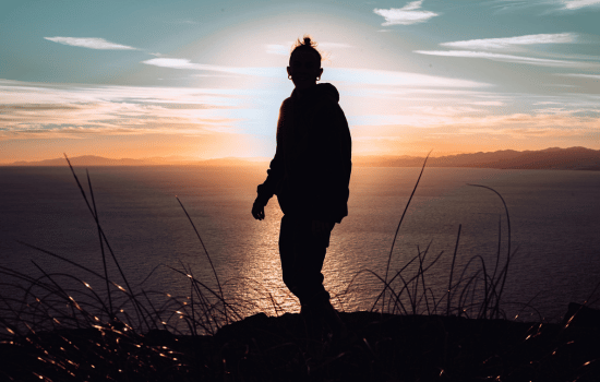 silhouette of a man standing on top of a mountain