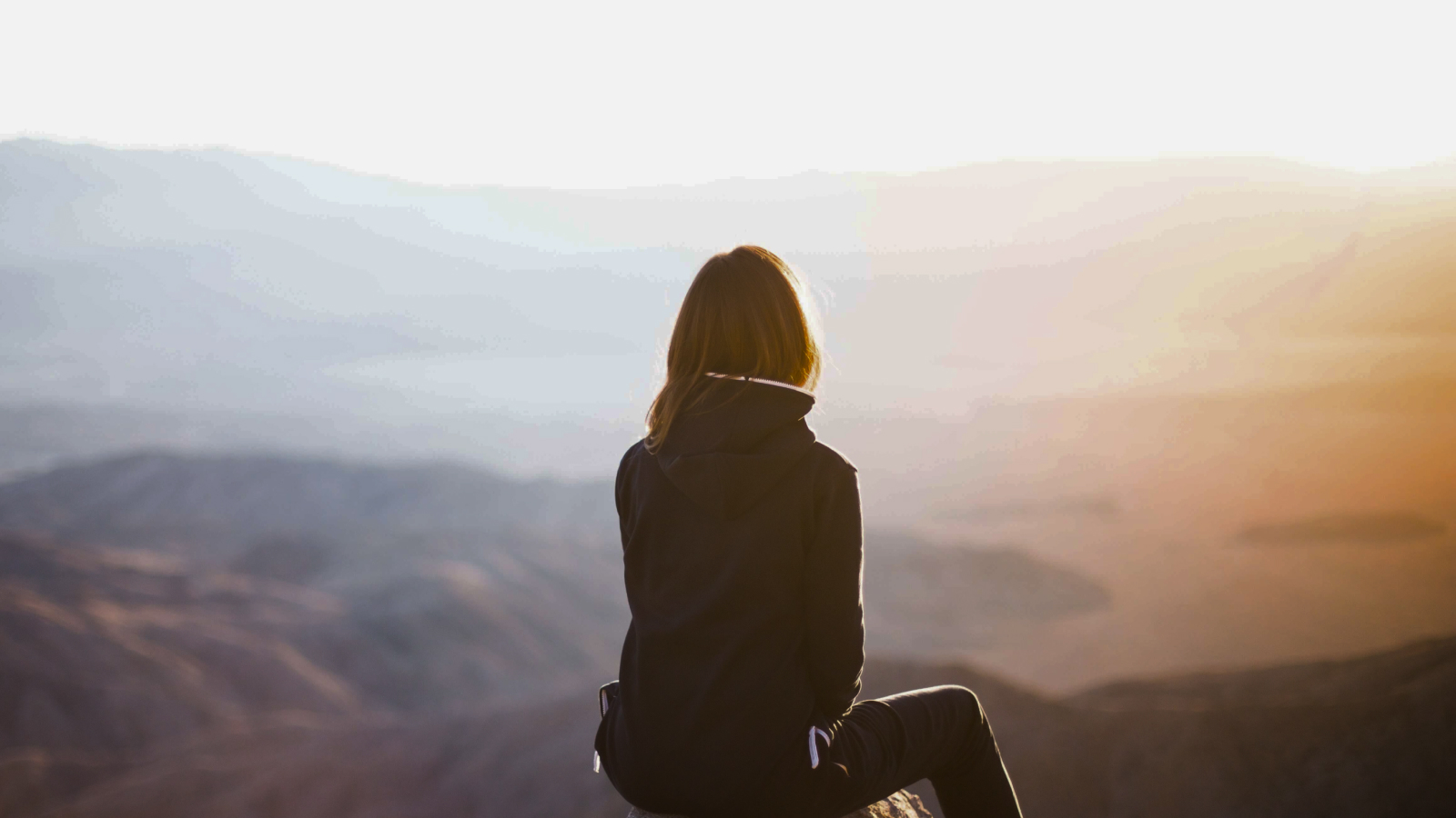 Woman sitting on mountain thinking about which OCD therapist in Seattle to choose.