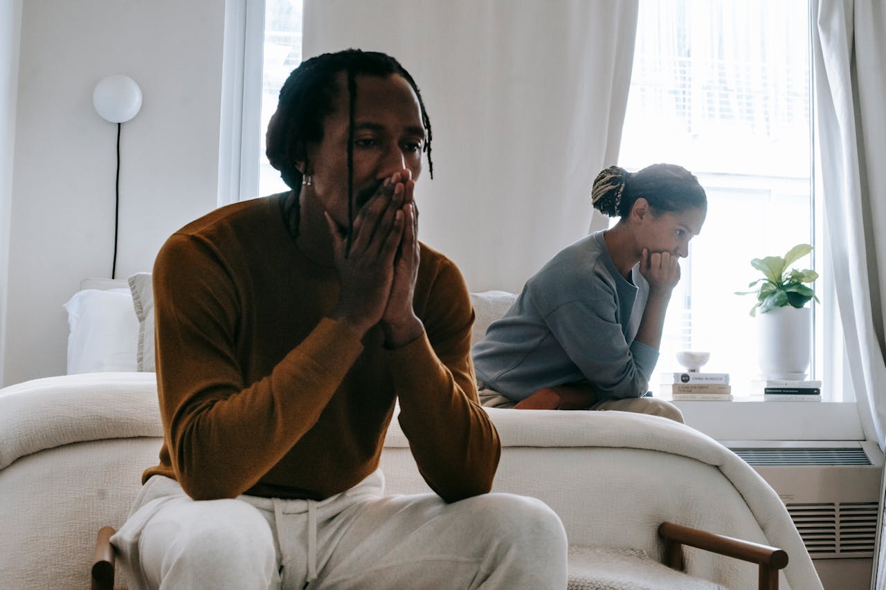 Unhappy couple sitting on bed after having argument