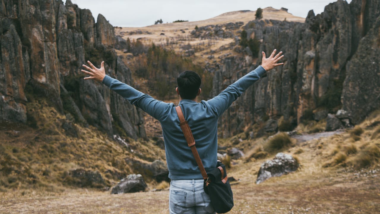 Person standing in a canyon with their arms outstretched away from the camera, thinking about healing your inner child.
