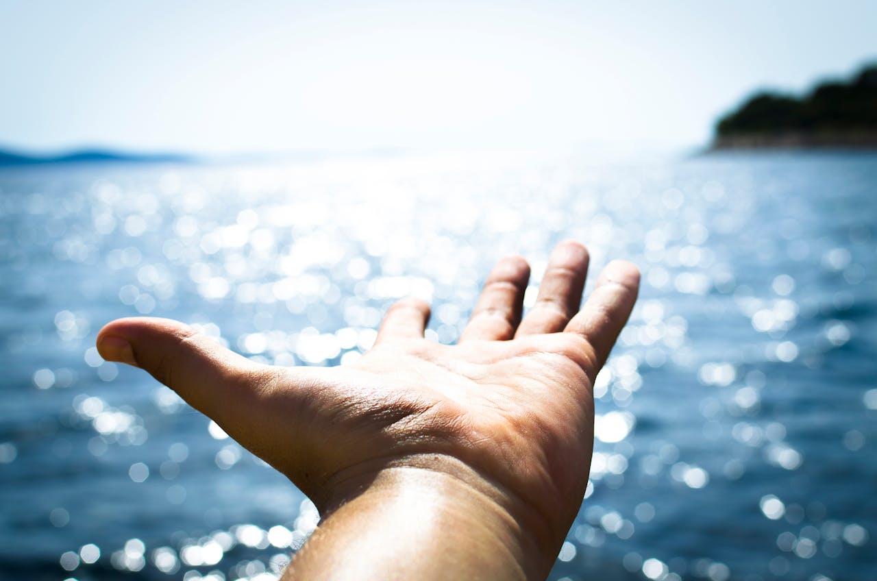 Person Hand Reaching Body of Water To Cope With Anxiety During Times of Uncertainty