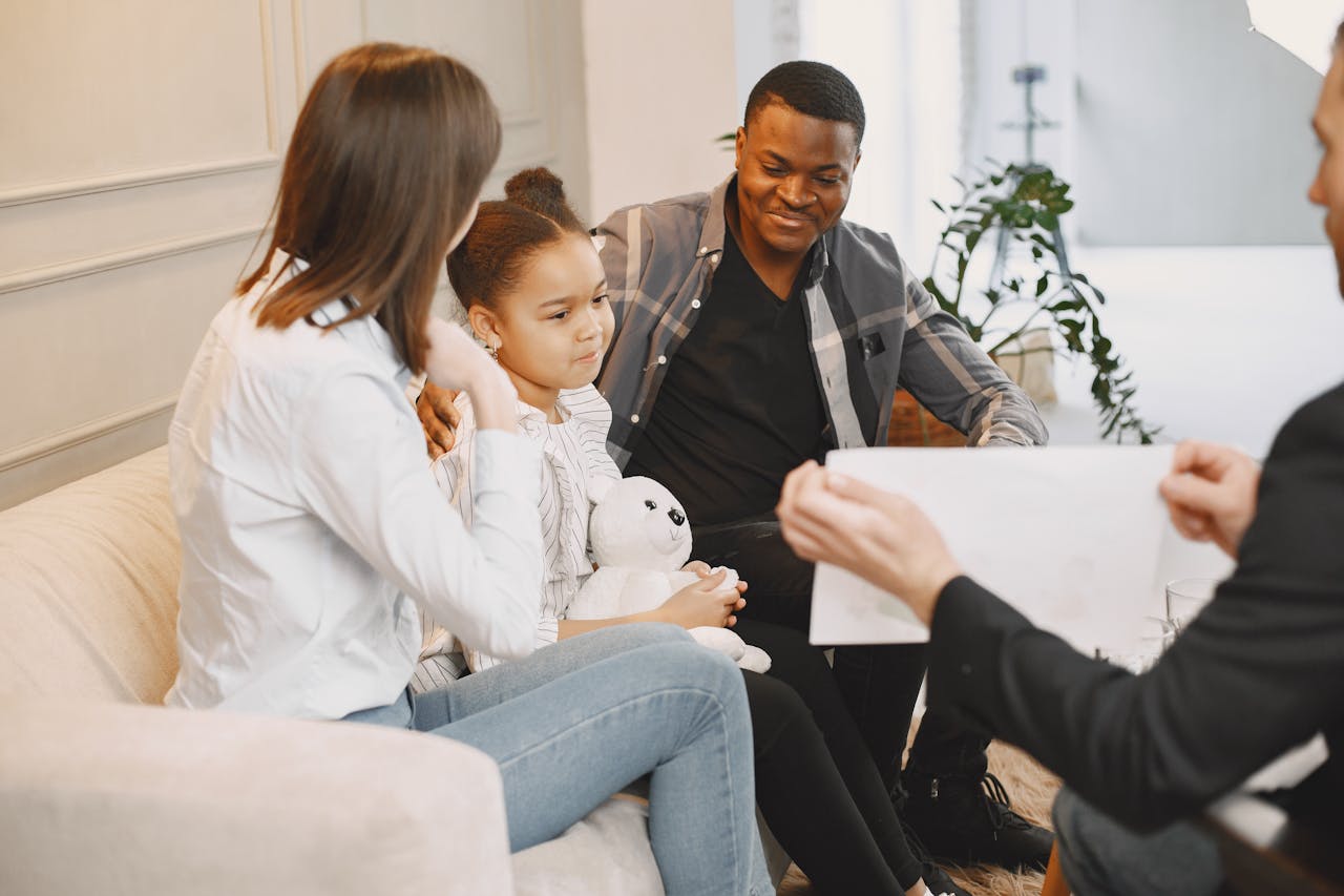 Photo of a Girl Looking at a Card with Her Parents Finding Support during Seattle Religious Abuse Therapy