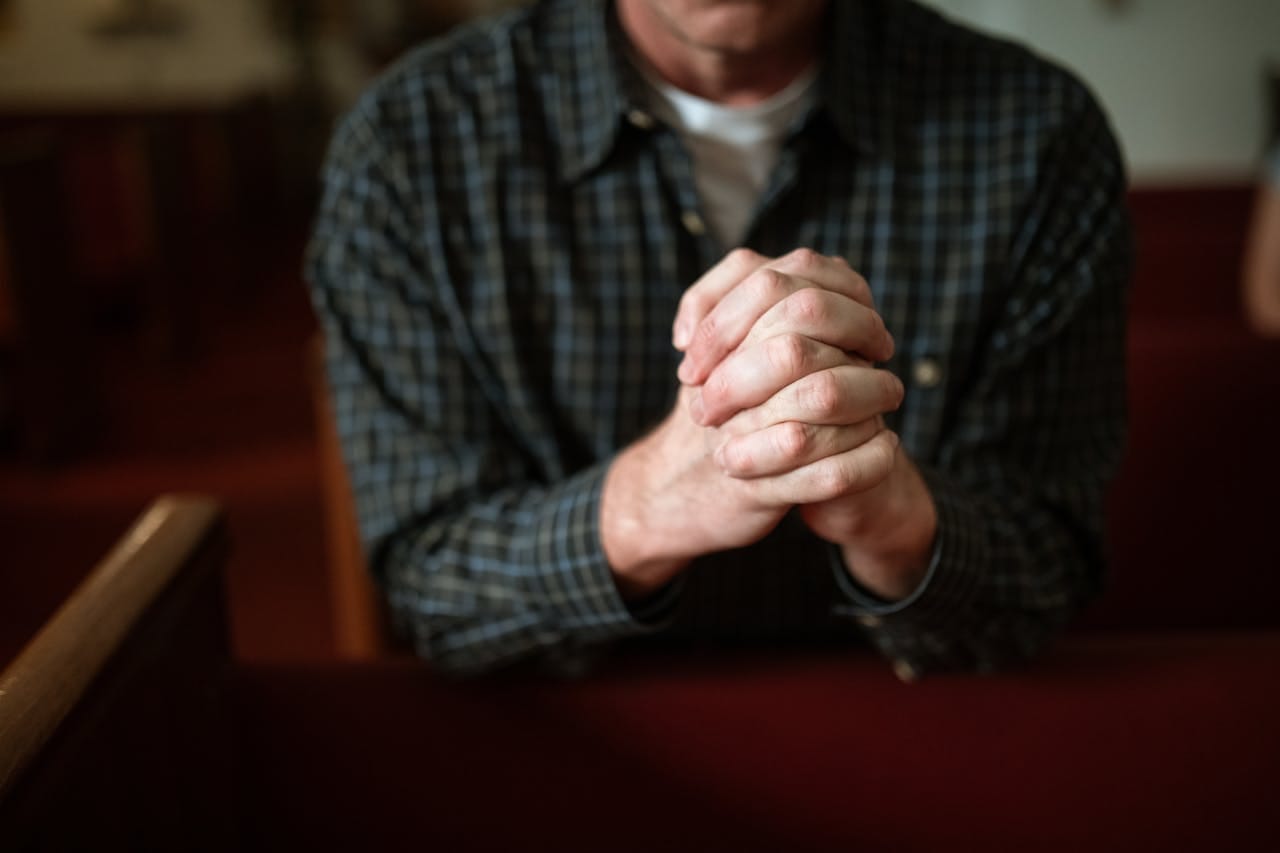 Person in Blue and Black Long Sleeve Shirt Praying