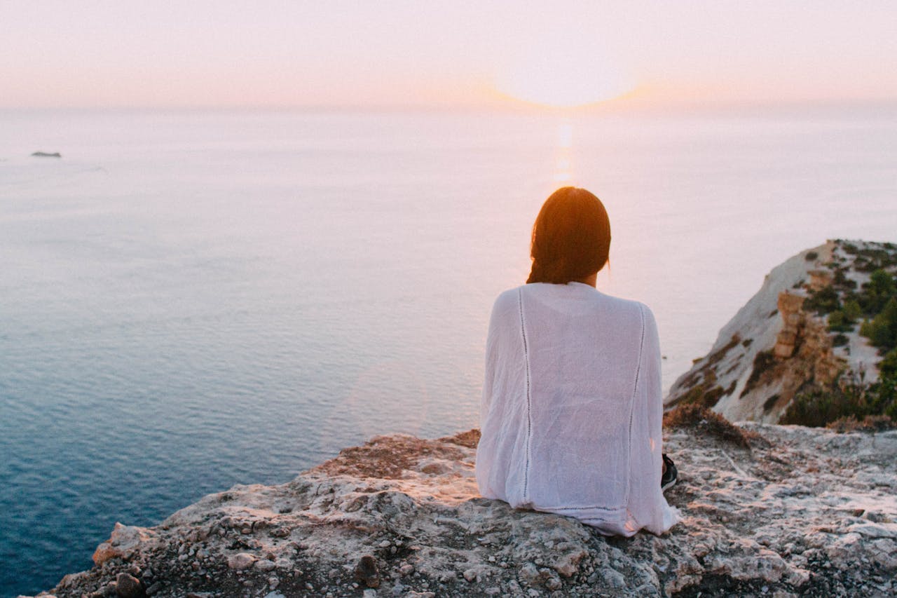 Person sitting on a cliff looking out at the ocean after attending therapy for perfectionism OCD.