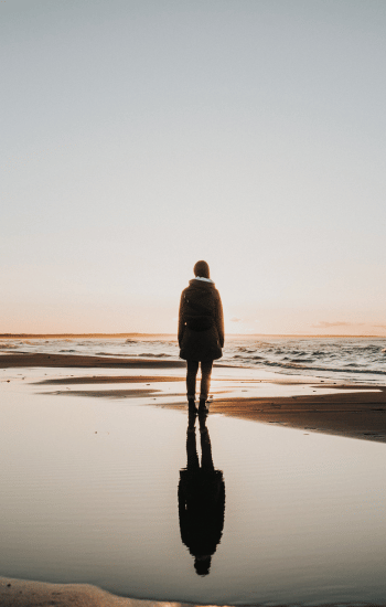 woman walking on the beach at sunset