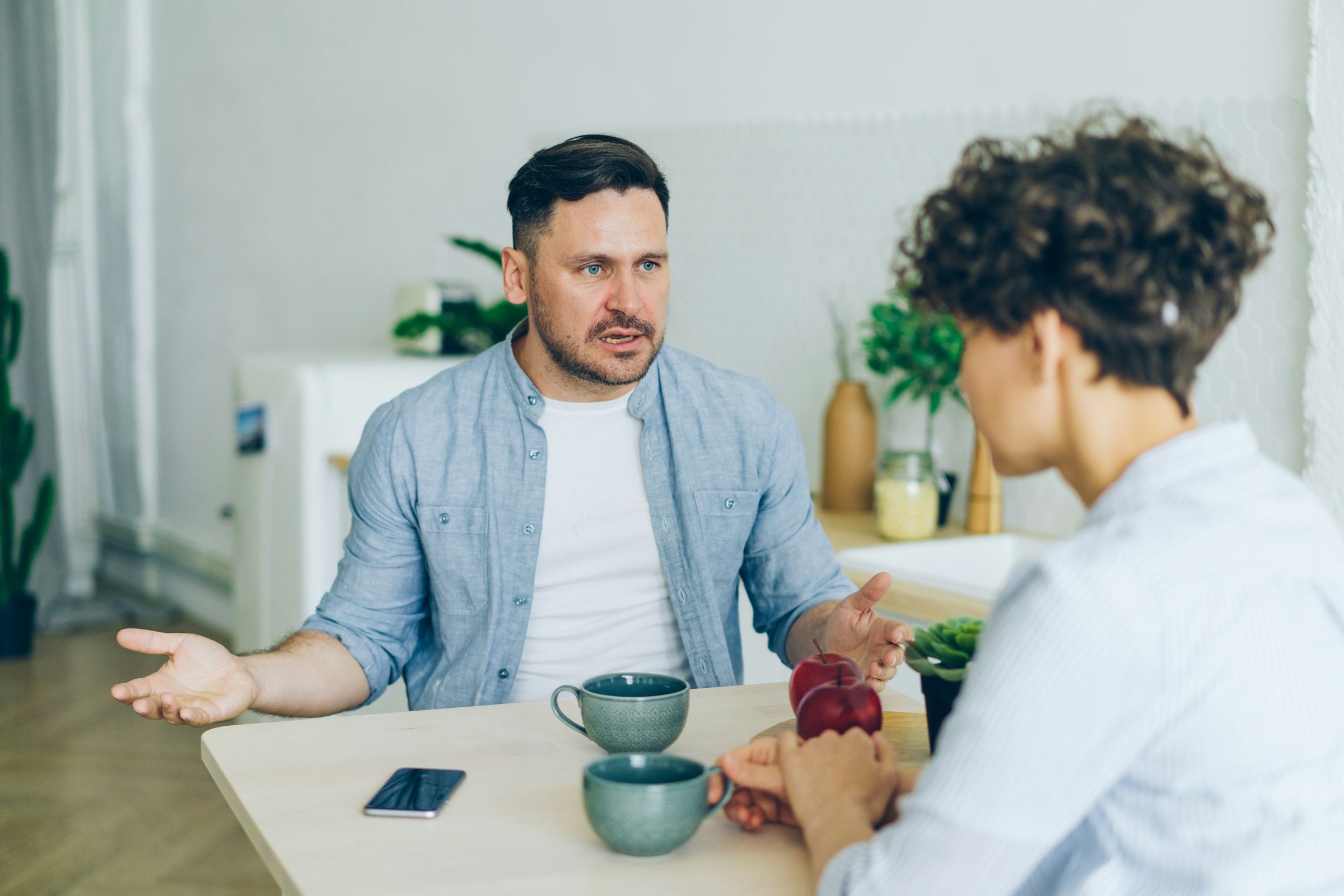 Two people sitting at a table arguing and discussing covert narcissism.