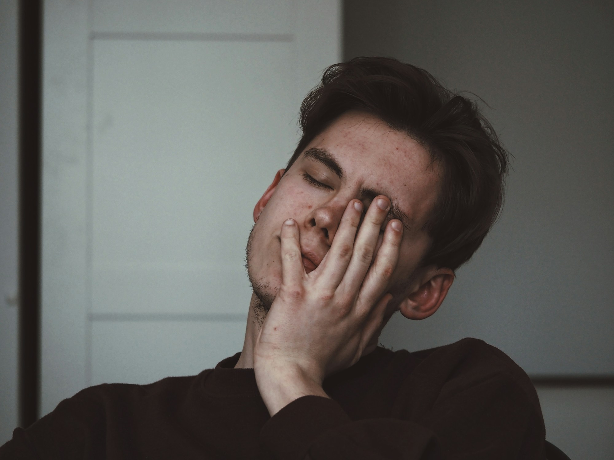Man sitting with his hand on his face thinking about hyper-independence and trauma.