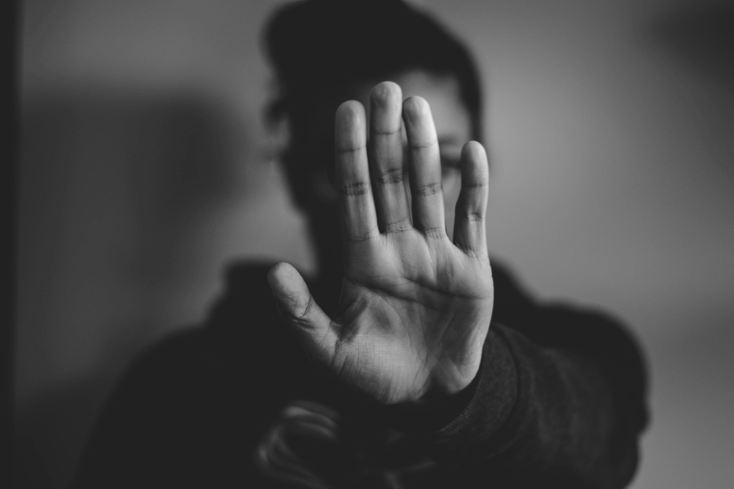 A grayscale photo of a woman holding her hand up after attending therapy for narcissistic abuse.