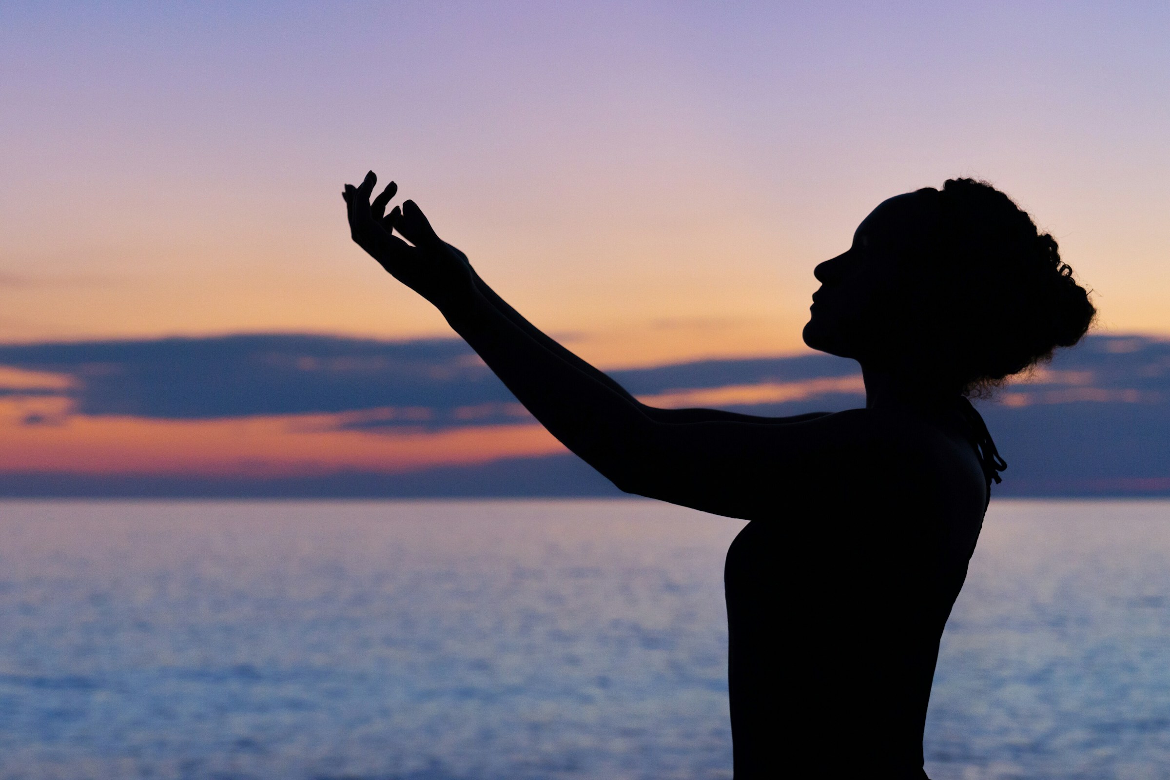 Silhouette of a woman holding up her hand at a beach after attending therapy for narcissistic abuse in Seattle.